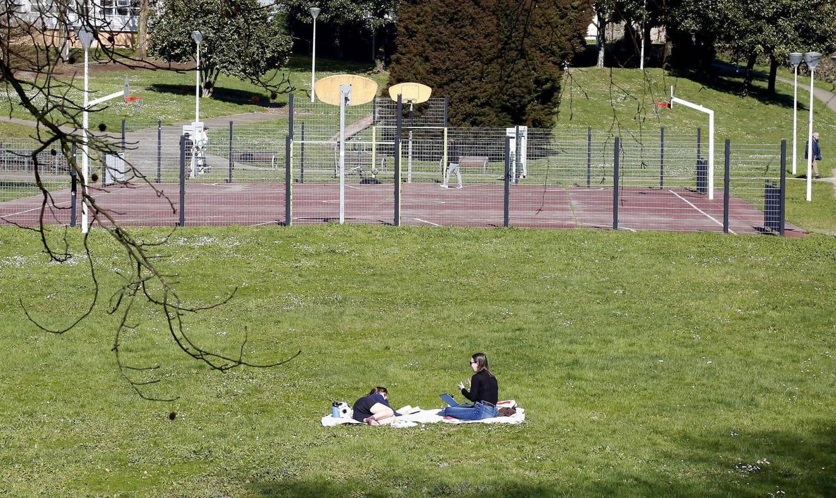 Dos mujeres disfrutan del tiempo soleado esta semana en un parque de Santiago