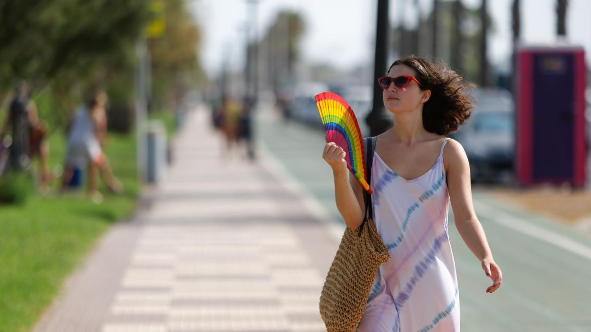 Una joven se abanica en plena calle, en esta ola de calor.