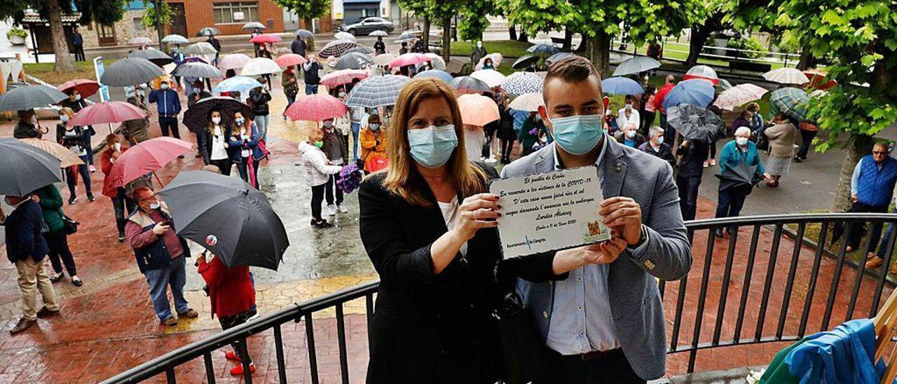 Carmen Arbesú y Enol González Zapico muestran la placa, con los asistentes al acto detrás.