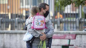 Un padre con mascarilla lleva a su hija en brazos el primer día de colegio el pasado septiembre.