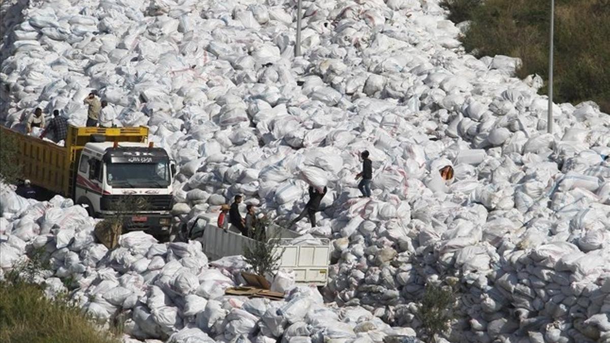 Varios operarios depositan bolsas de basuras sobre la gran montaña de residuos apilados en una calle del barrio de Al Fanar, en Beirut, este viernes.