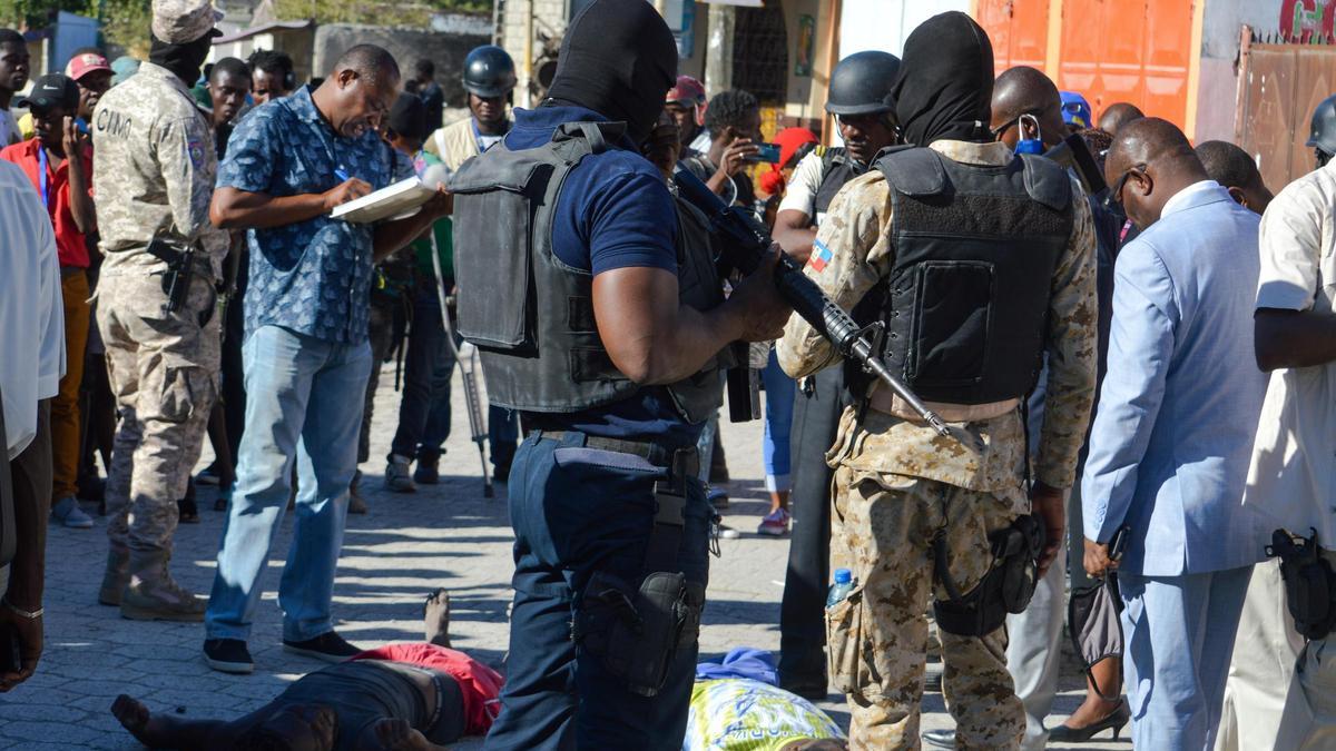 Varias personas y la Policía rodean dos cadáveres tras el motín en una cárcel de Puerto Príncipe.