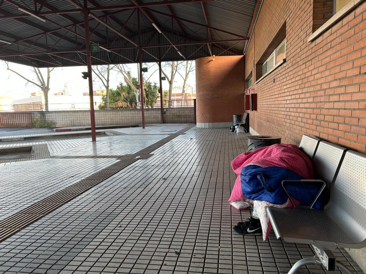 Una persona duerme en un banco de la estación de autobuses