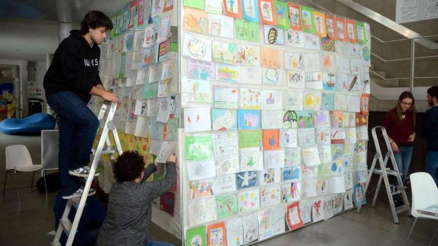 Alumnos de la Facultad de Ciencias de la Educación pegando dibujos en el cubo. // Rafa Vázquez