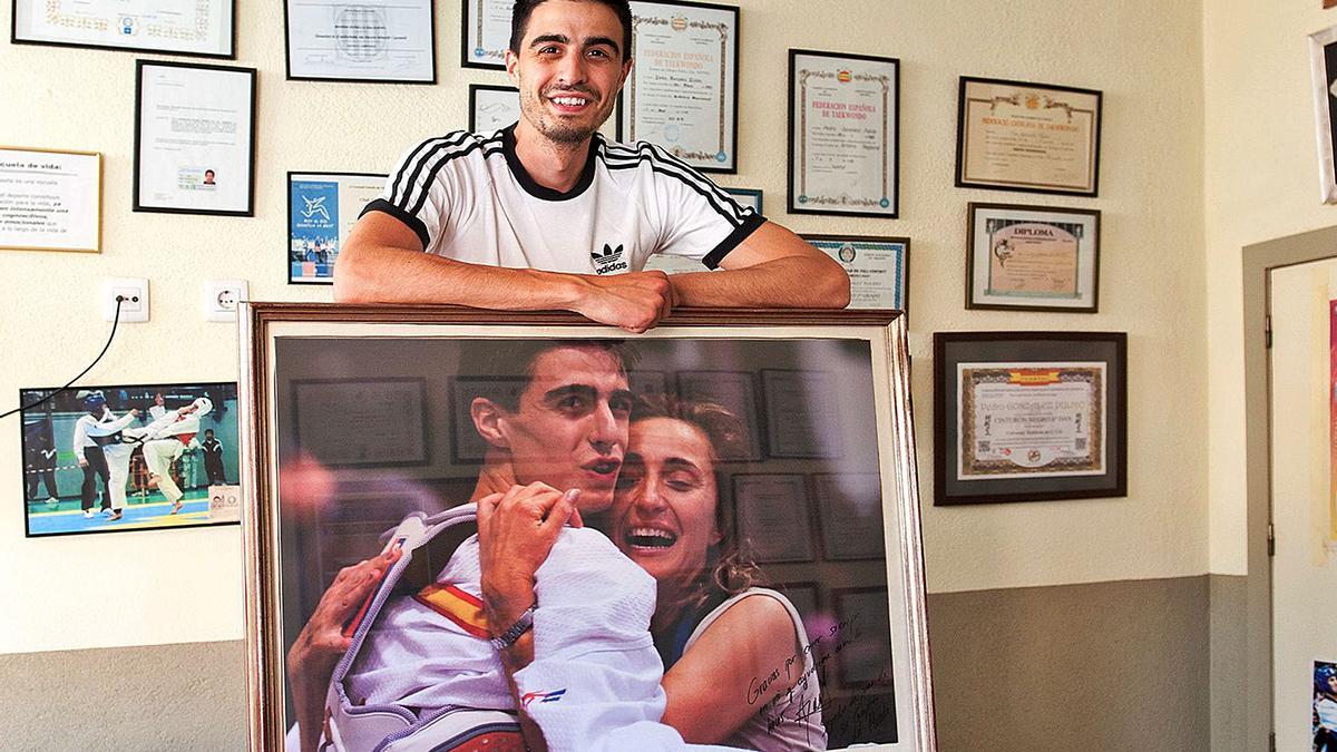 Joel González, a la seva casa de Vilafant, amb un retrat històric, abraçat amb la seva mare després del primer Mundial (2009). | CONXI MOLONS