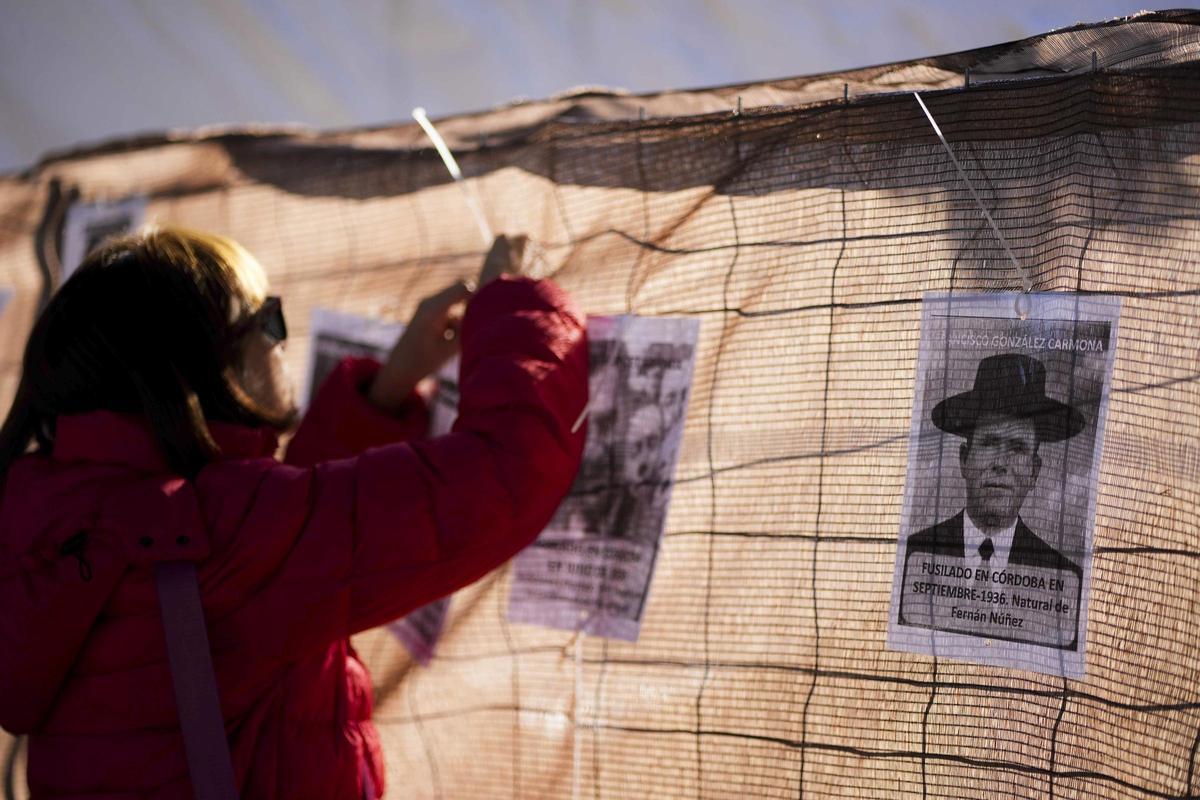 Una mujer coloca una foto en la valla que circunda la zona de trabajos.