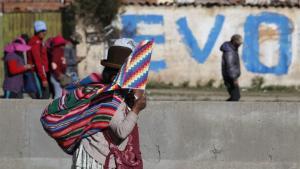 Una mujer protesta en las calles de Bolivia con la bandera indígena.