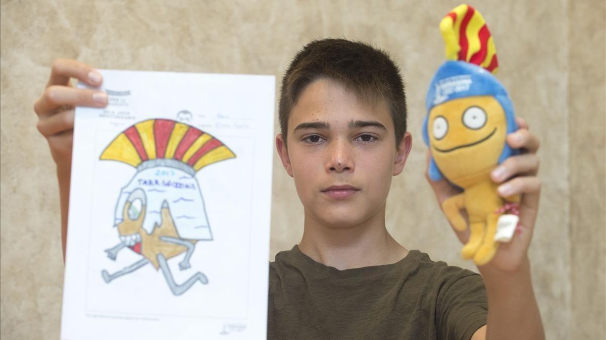 Aleix Girona sostiene el dibujo original con el que ganó el concurso de la mascota Tarracus, de la que sostiene el muñeco definitivo.