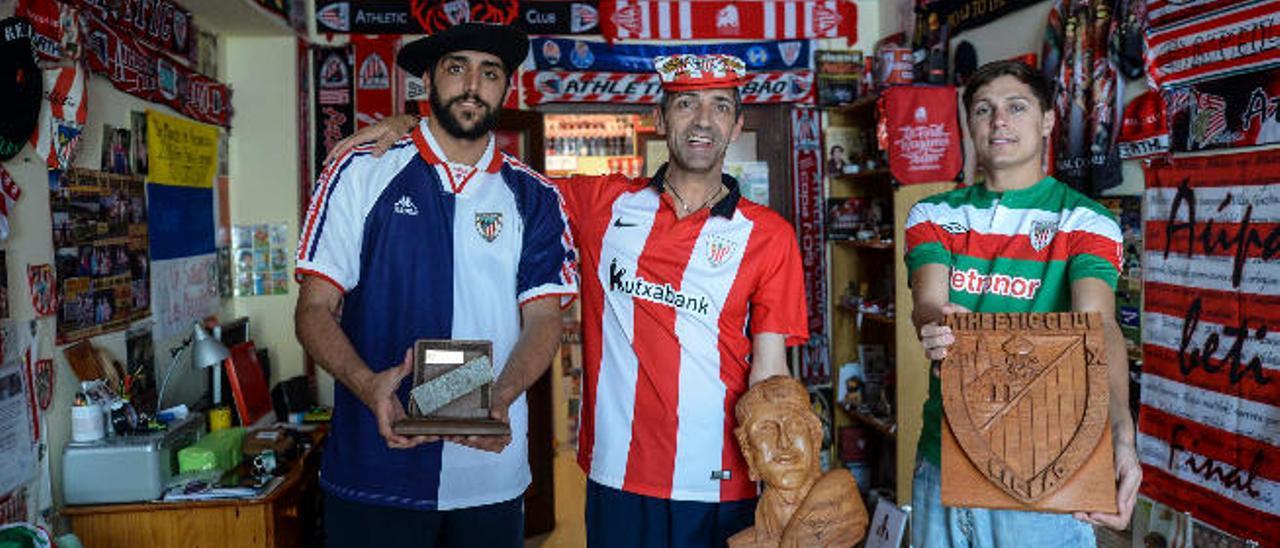 Aitor, Chano y Nelson, de izquierda a derecha, sostienen en su casa diferentes placas del Athletic.