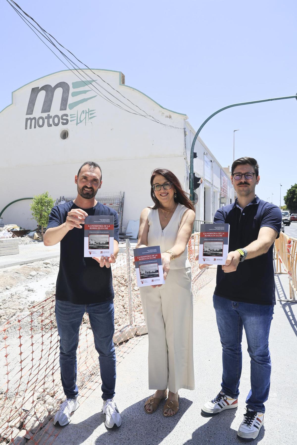 Los autores muestran el libro delante de parte del complejo fabril de Sánchez Rojas, en la avenida de Santa Pola de Elche