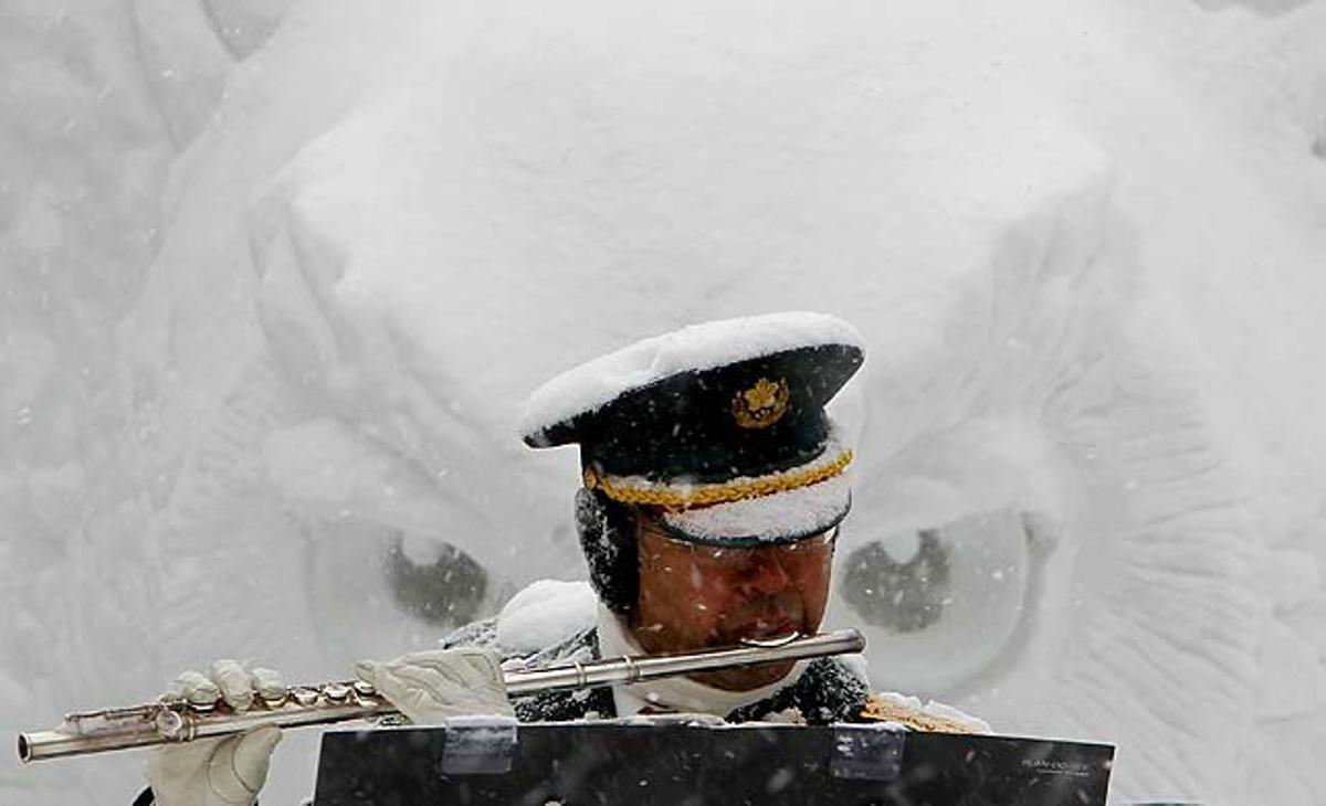 Un membre de les Forces d’Autodefensa del Japó toca la flauta travessera davant d’una escultura de neu semblant a un mussol, en la cerimònia d’obertura del 62 festival de la neu de Sapporo a Sapporo (Japó).