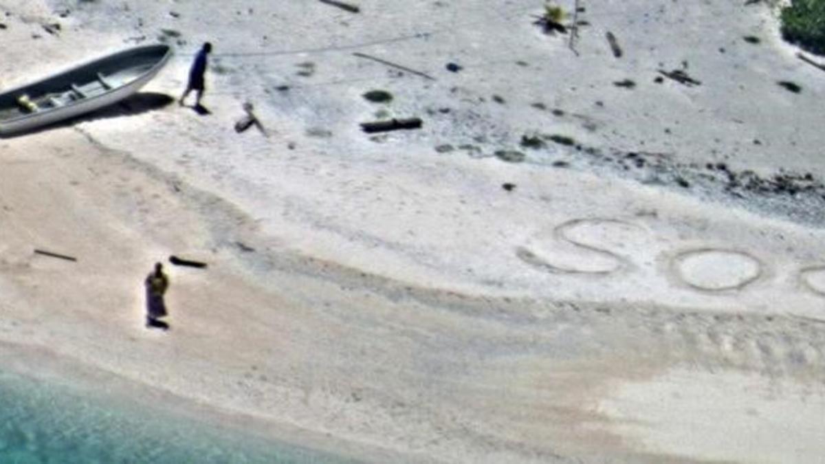 SOS escrito en la arena de playa por  Linus y Sabina Jack.