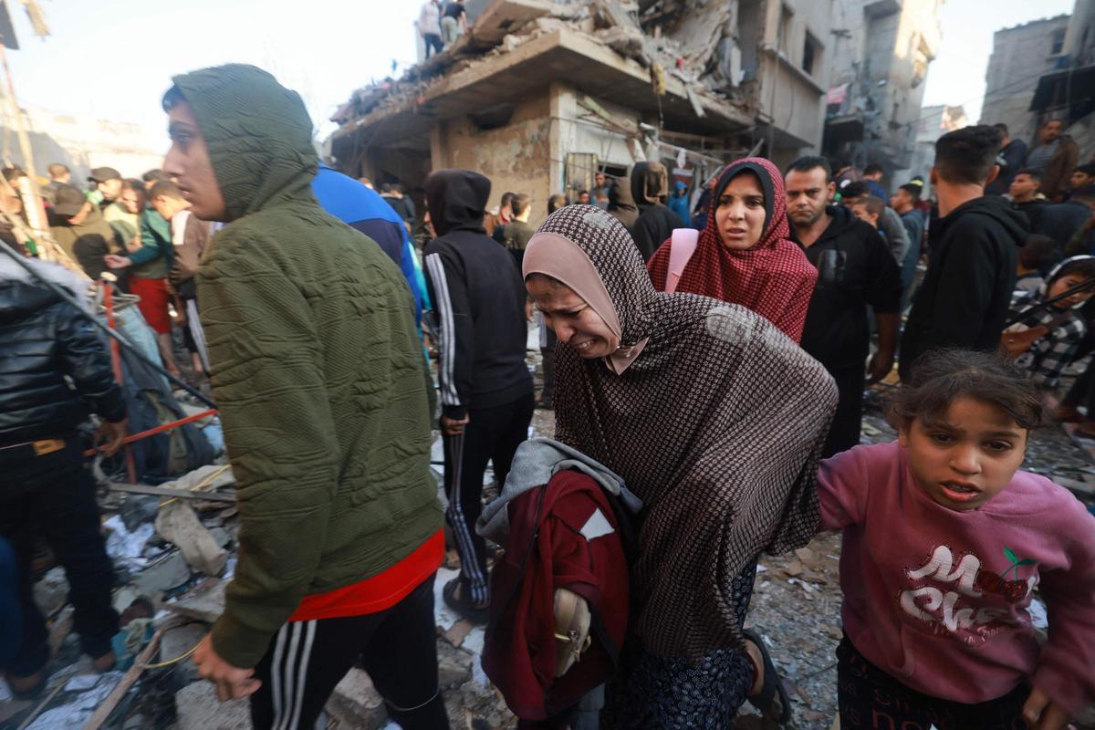 Un joven palestino carga a un niño gravemente herido mientras la gente sale corriendo de una zona bombardeada en el campo de refugiados de Rafah, en el sur de la Franja de Gaza, el 1 de diciembre de 2023, cuando los combates se reanudaron poco después de la expiración de una tregua de siete días entre Israel y los militantes de Hamás.