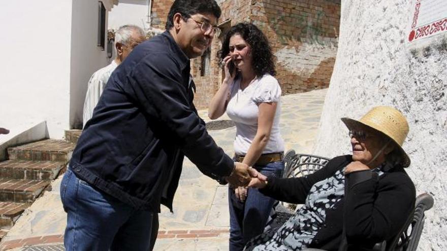 El coordinador general de Izquierda Unida LV-CA, Diego Valderas (i), saluda a una mujer antes del encuentro que ha tenido con simpatizantes en el salón de astos del antiguo Ayuntamiento del municipio malagueño de Totalán.