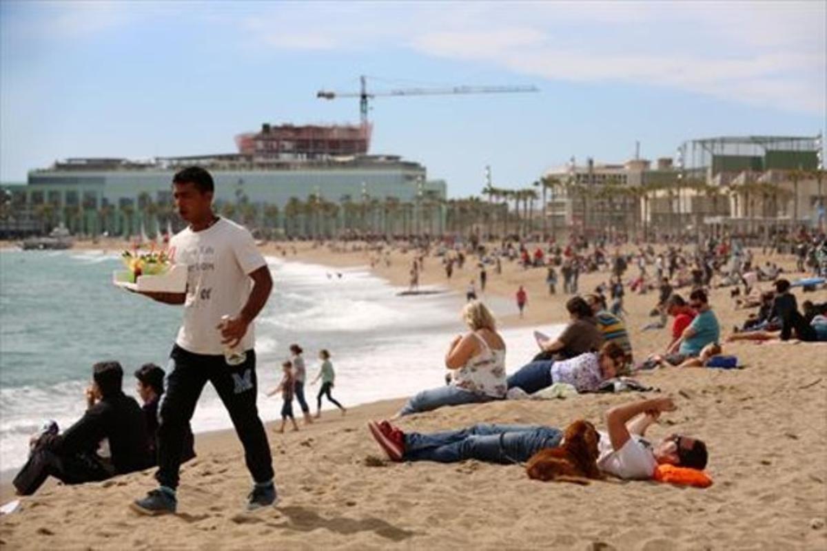 Un home es passeja per la platja carregat amb una safata de combinats, la primavera passada.