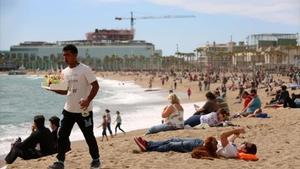 Un home es passeja per la platja carregat amb una safata de combinats, la primavera passada.