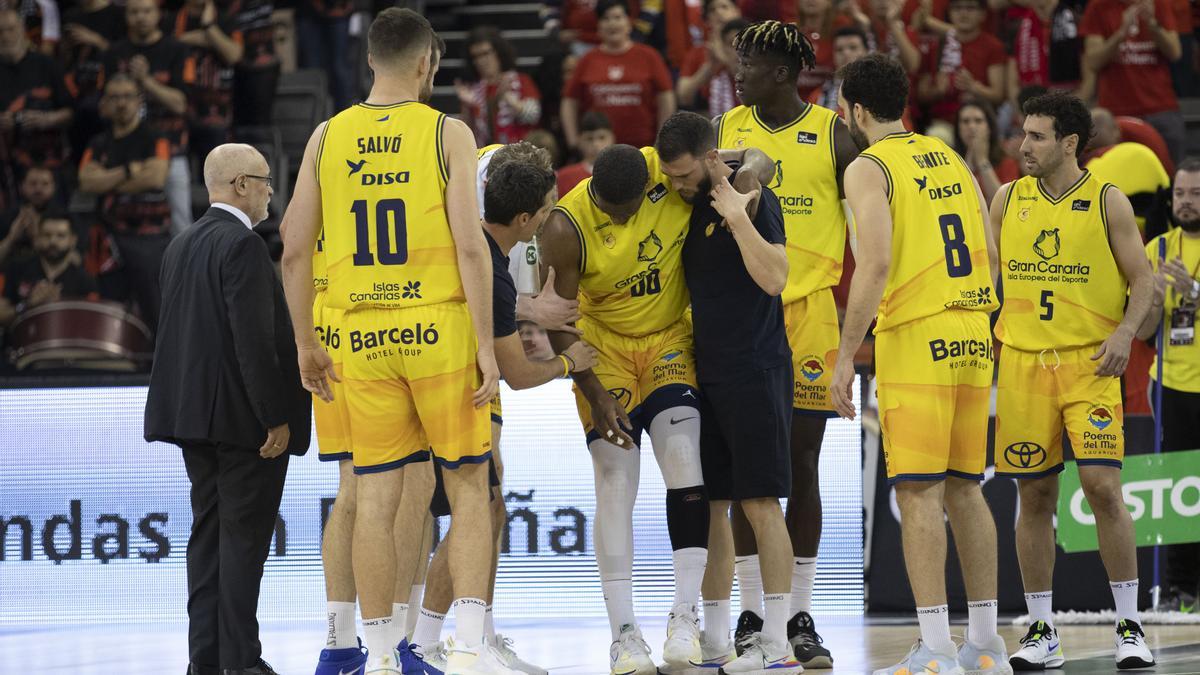 Damien Inglis, adolecido de la rodilla izquierda, se apoya en la espalda de Lionel Montelongo, fisio del Granca