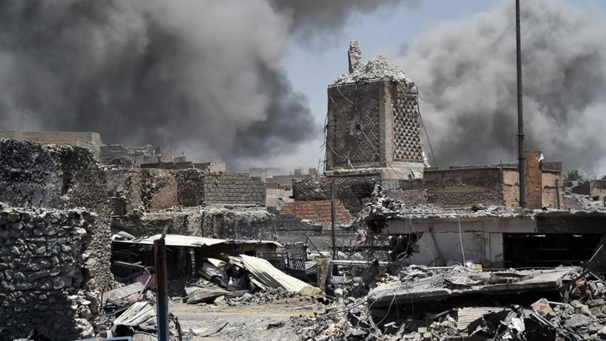 Una humareda se aprecia detrás de la base de la histórica mezquita destruida en Mosul.