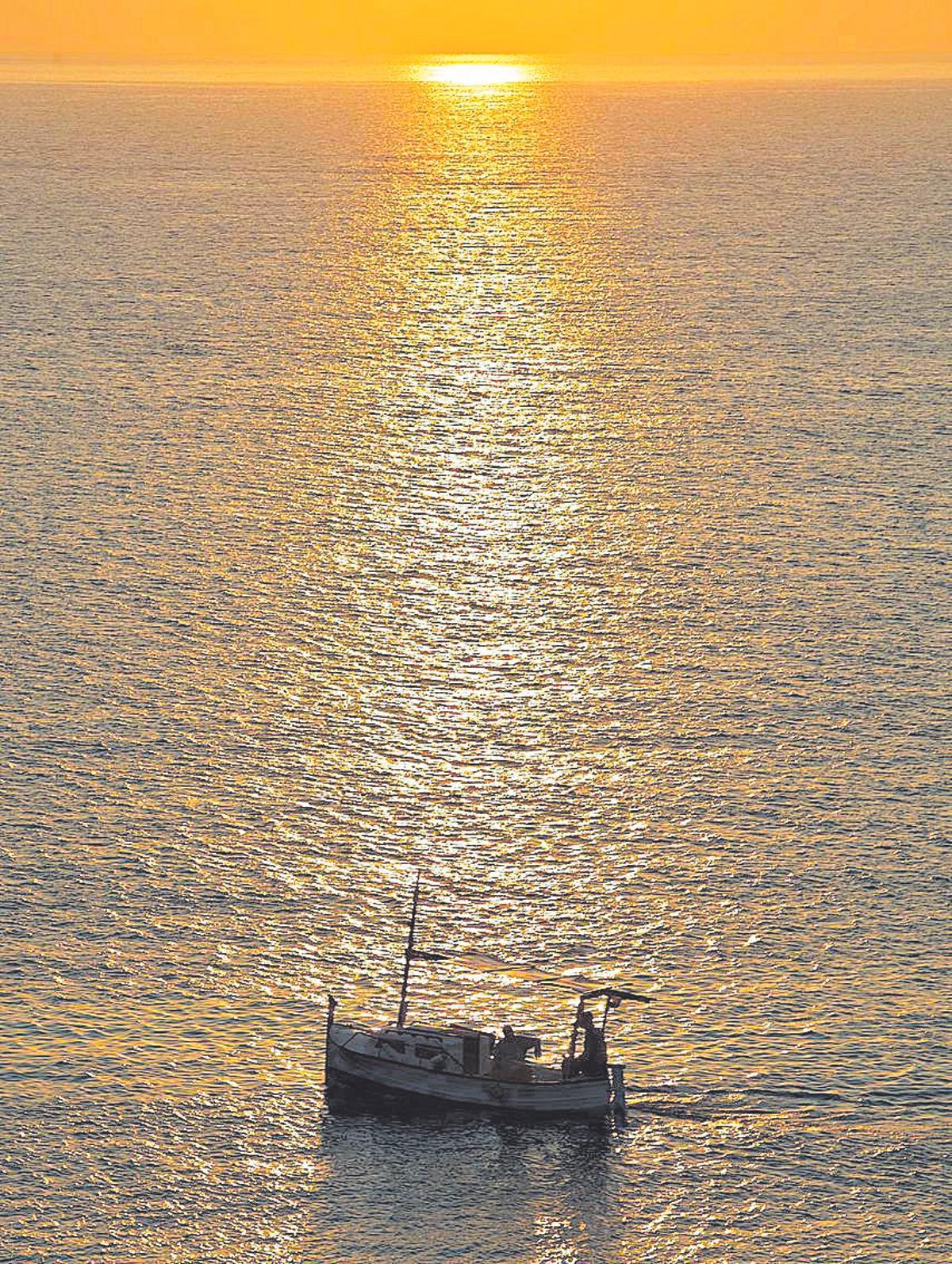 Un barco de pesca navegando en la zona de Cap Martinet al amanecer.