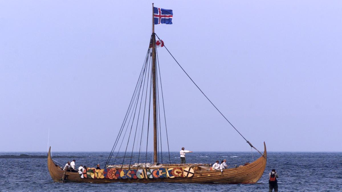 FILE PHOTO: A tourist (R) photographs the Viking replica ship the Islendingur as it arrives in the fishing village of L'Anse aux Meadows in Newfoundland July 28, 2000. REUTERS/File Photo