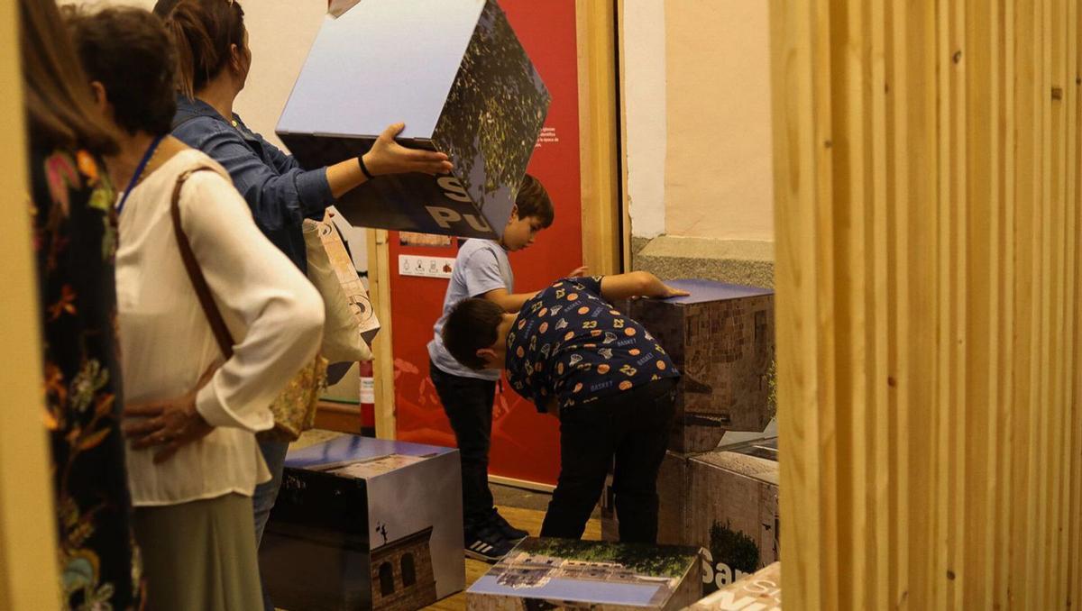 Varios niños juegan con cubos ilustrados con fachadas de templos. | ALBA PRIETO