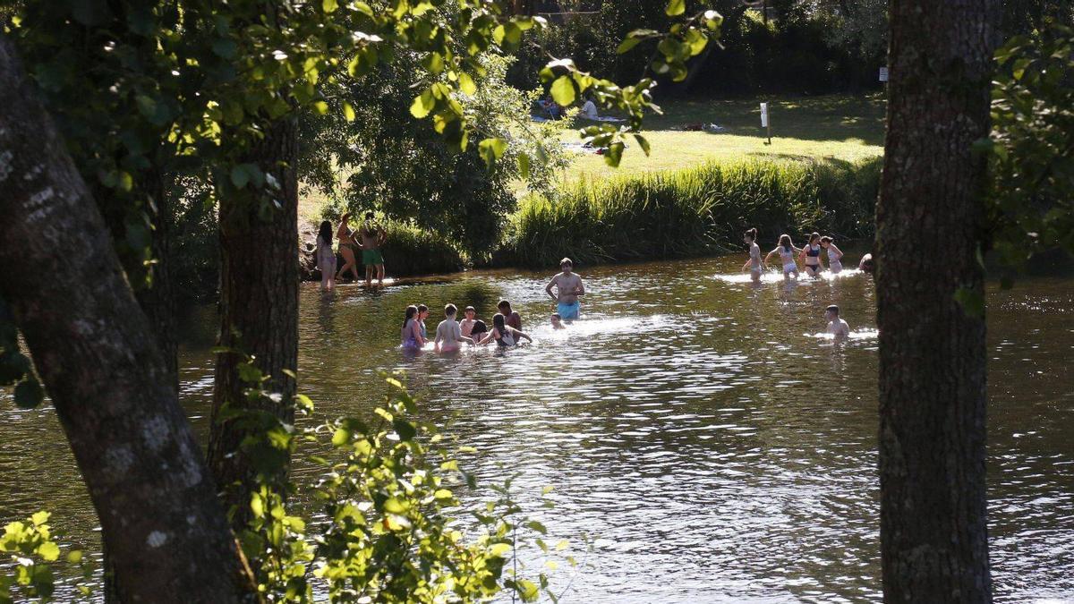 Bañistas en A Praíña, a escasos metros de donde se ubicará el complejo turístico.