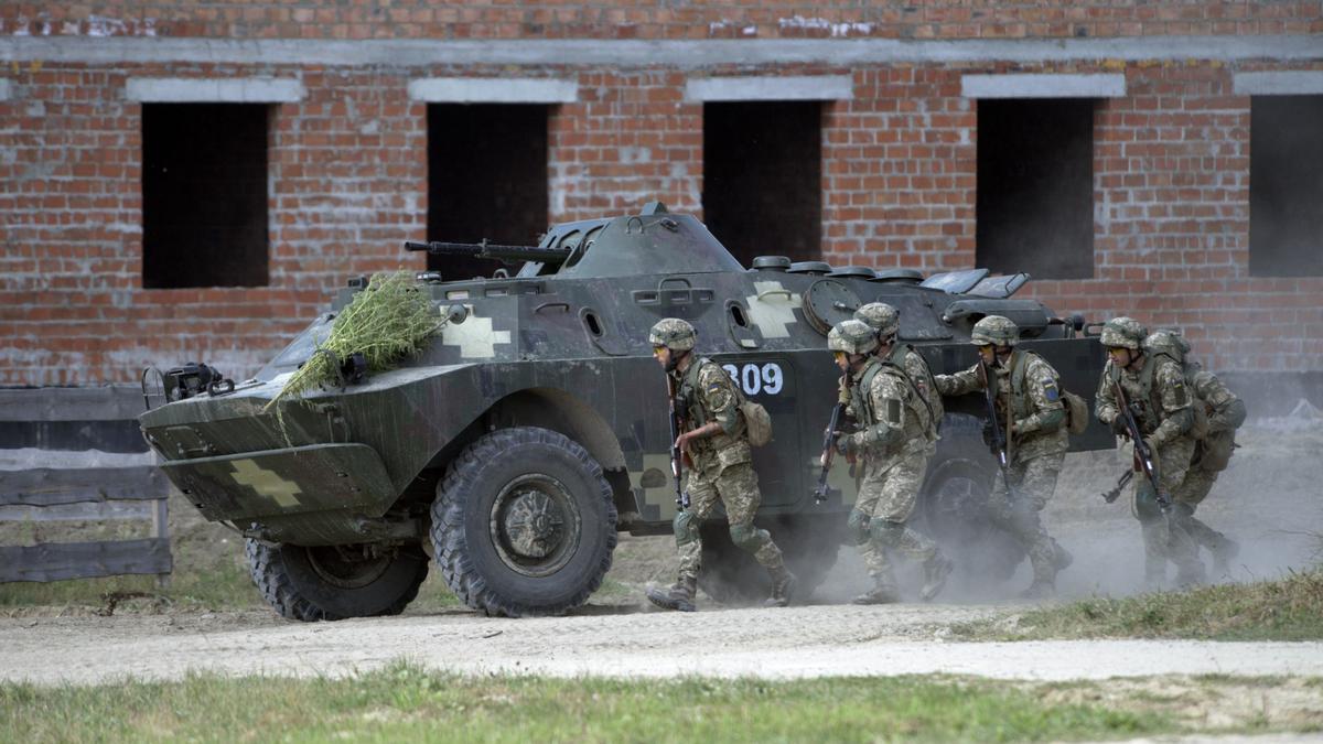 Soldados caminan junto a un blindado.