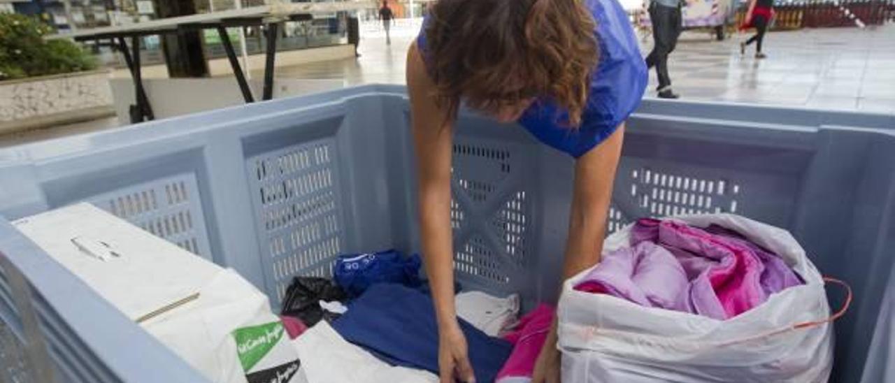 Una voluntaria guarda en un contenedor una bolsa de ropa, ayer.