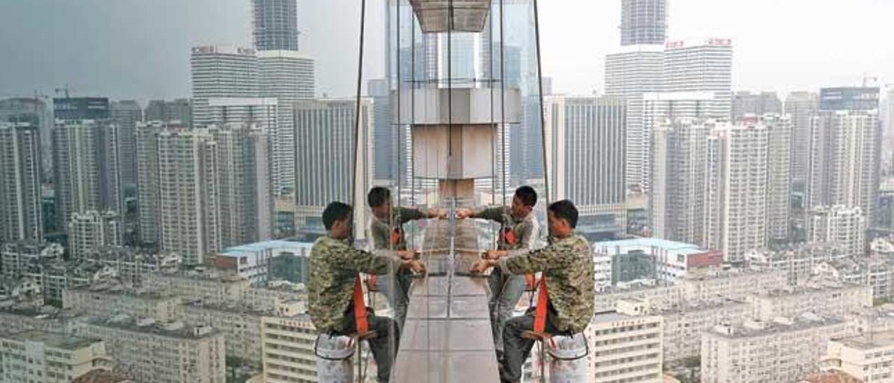 Unos trabajadores limpian los cristales de un edificio de treinta plantas en Qingdao, en China.