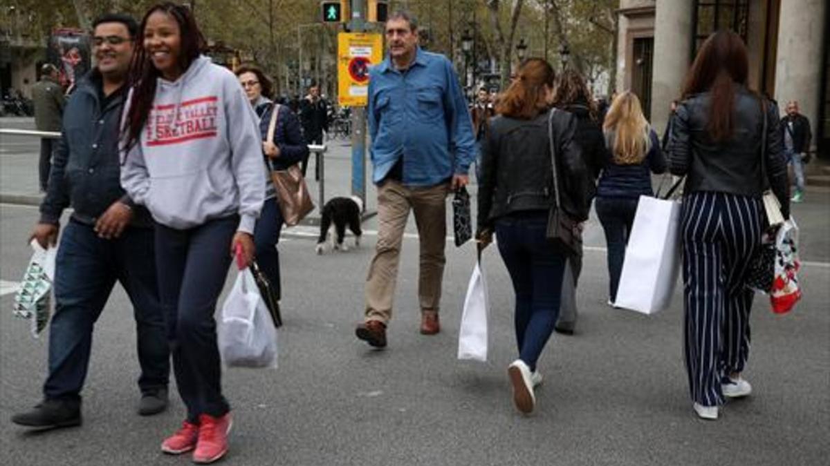 Con bolsas de tiendas 8Viandantes en el paseo de Gràcia de Barcelona.