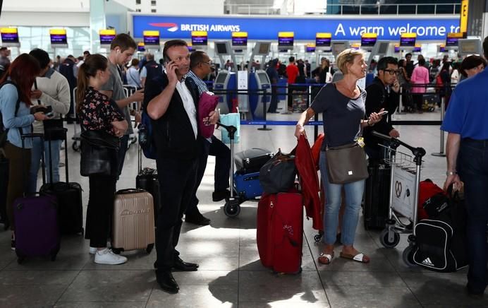 People wait with their luggage at the British ...