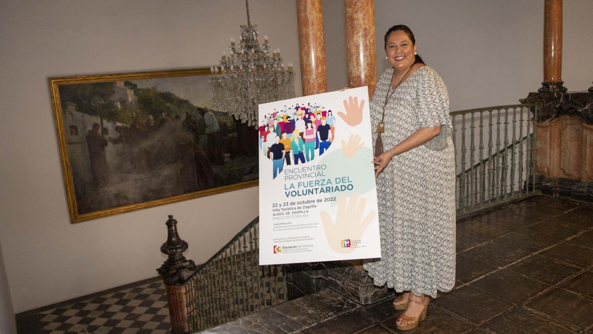 Dolores Amo, con el cartel anunciador del encuentro de voluntarios.