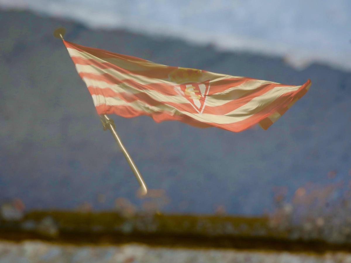 La bandera del Sporting reflejada en un charco en Mareo.