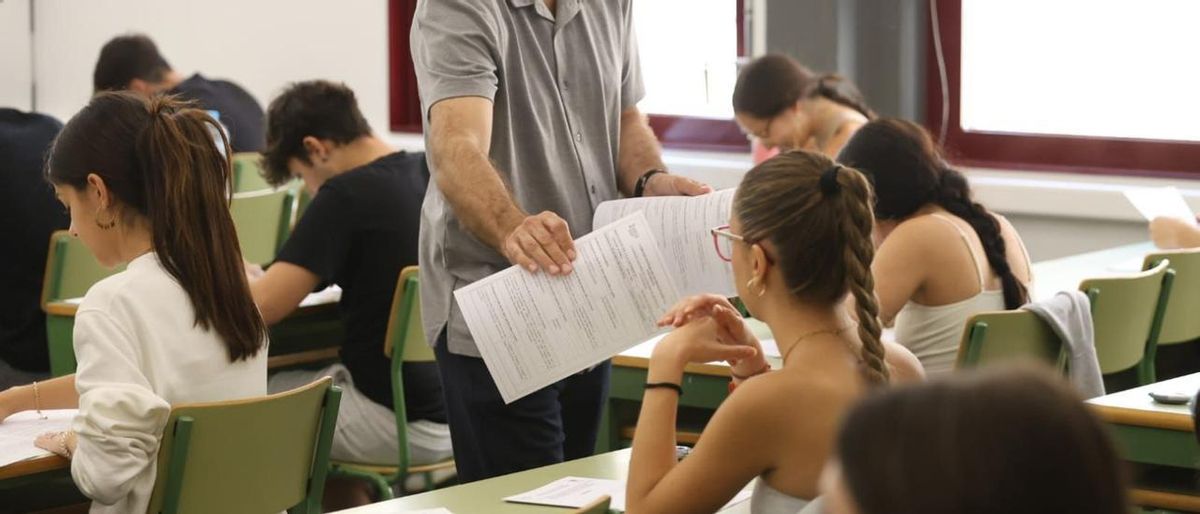 Imagen de archivo de un profesor repartiendo exámenes en la EBAU 2023.