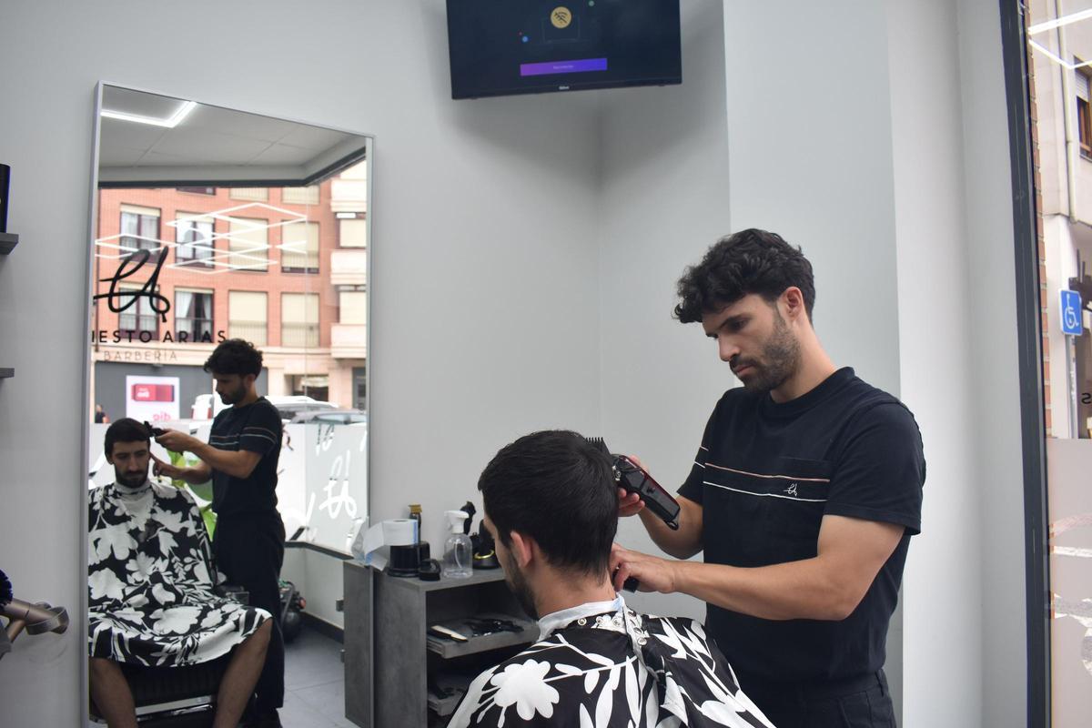 Ernesto Arias cortando el cabello a un cliente en Nava.
