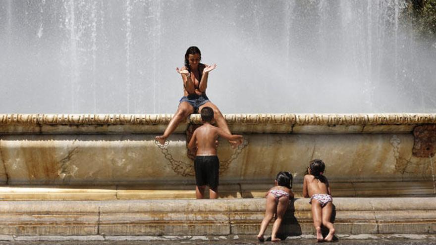 Niños y jóvenes se refrescan en una fuente en Sevilla.