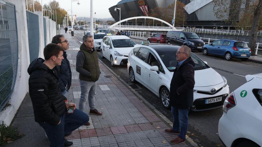 Un grupo de taxistas, ayer, frente al recinto ferial Luis Adaro. | Juan Plaza