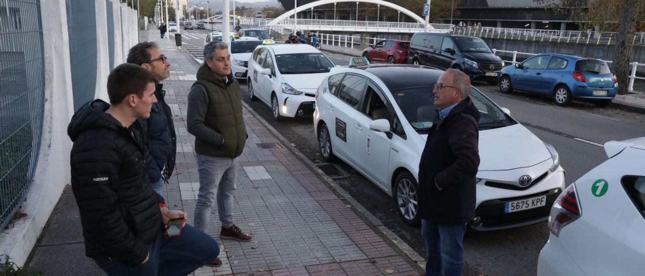 Un grupo de taxistas, ayer, frente al recinto ferial Luis Adaro. | Juan Plaza