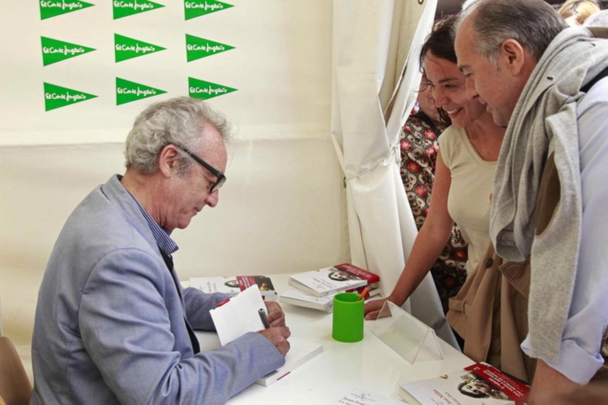 El escritor Juan José Millas firma autografos a los lectores que se han acercaron a su parada para celebrar la ’diada’ en Barcelona.