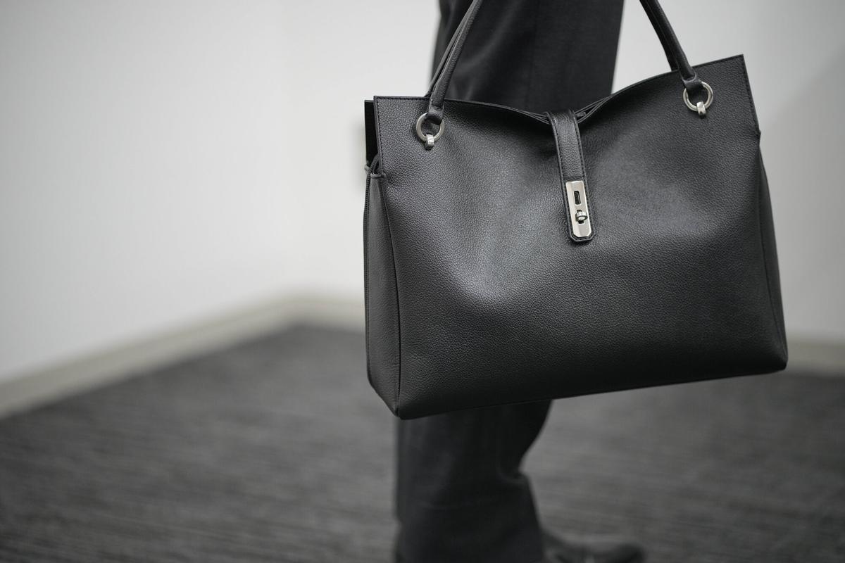 Takanori Kobayashi, a public relations officer at Hamano Leather Crafts Co., Ltd., a long-established Japanese maker of leather goods, holds the same model of handbag used by Prime Minister Sanae Takaichi, Tuesday, Dec. 2, 2025, in Tokyo. (AP Photo/Eugene Hoshiko)