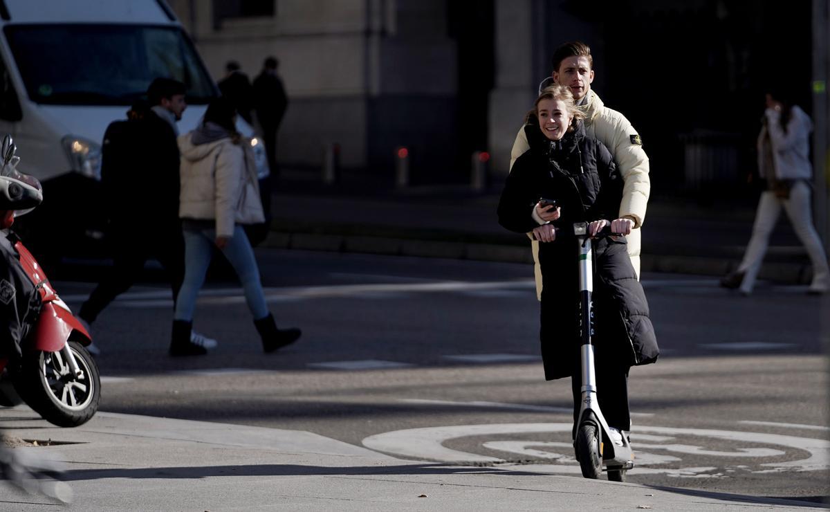 Dos jóvenes circulan en patinete eléctrico por el centro de Madrid