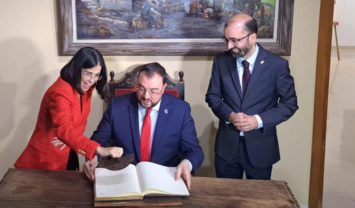 Adrián Barbón firma en el libro de la Casa de Cultura de Cangas del Narcea  ante Carolina Darias y el alcalde, José Víctor Rodríguez. | A. L.