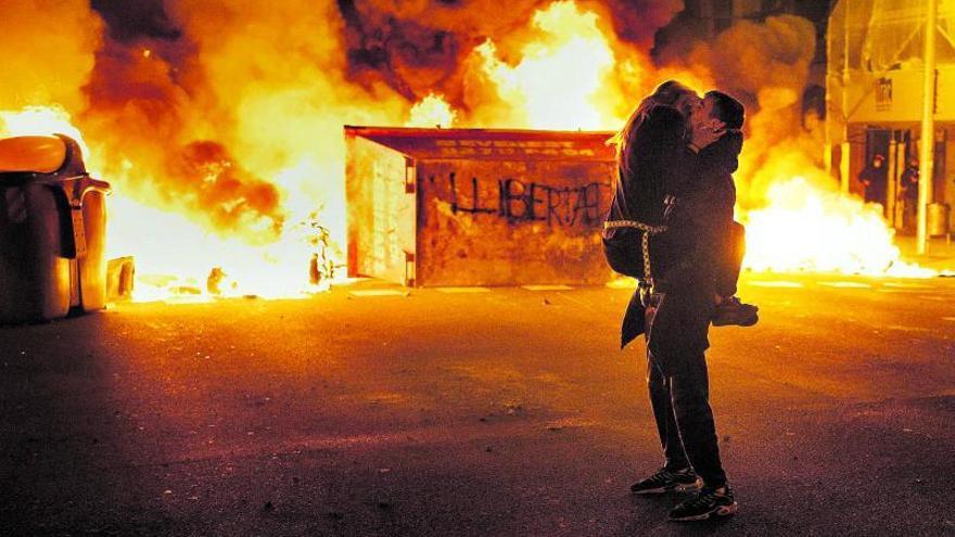 Una pareja se abraza frente a una barricada en la segunda noche de protestas en Barcelona para reclamar la libertad del rapero Pablo Hasél.