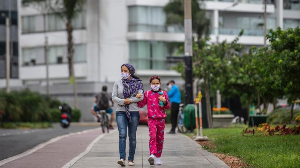 Una mujer y su hija pasean por una calle de Lima,