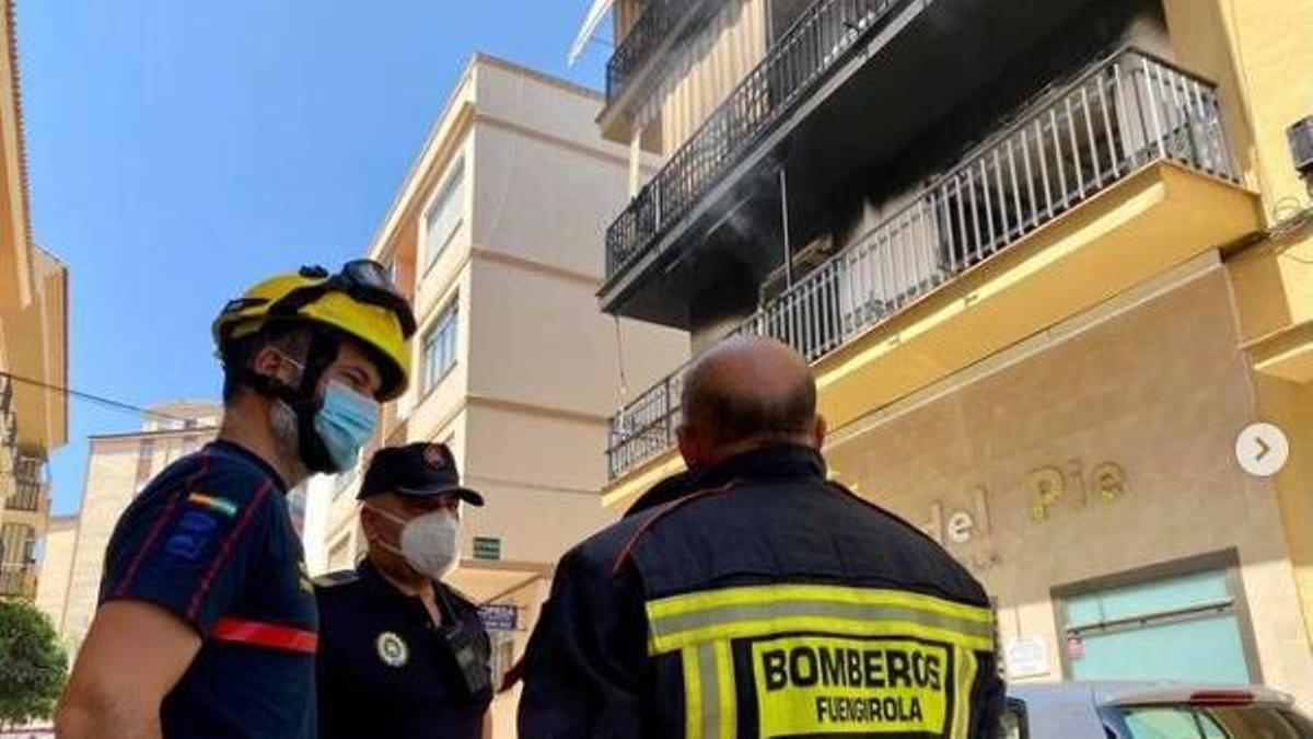 Varios bomberos con la vivienda siniestrada en segundo plano.