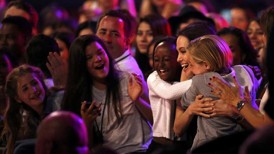 Liam Hemsworth (arriba) y Emma Stone (i), y Angelina Jolie abrazada por sus hijos en la fiesta de los premios.