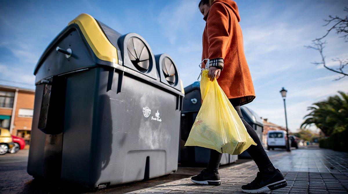 Una mujer recicla envases de plástico en el contenedor amarillo.