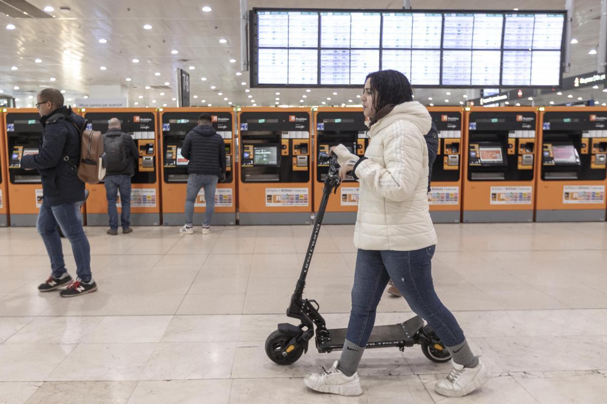 Una usuaria de Rodalies con un patinete eléctrico en la Estación de Sants, el primer día de prohibición