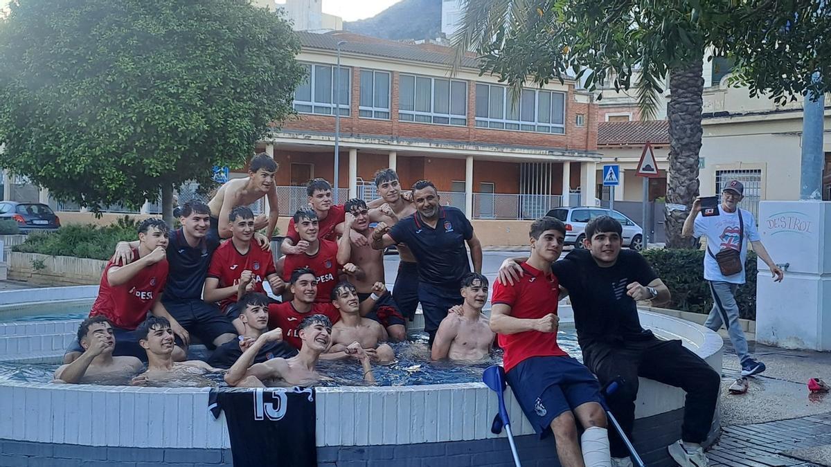 Jugadores y técnicos del juvenil "B" de la UE Tavernes de la Valldigna celebran su doble éxito en la fuente