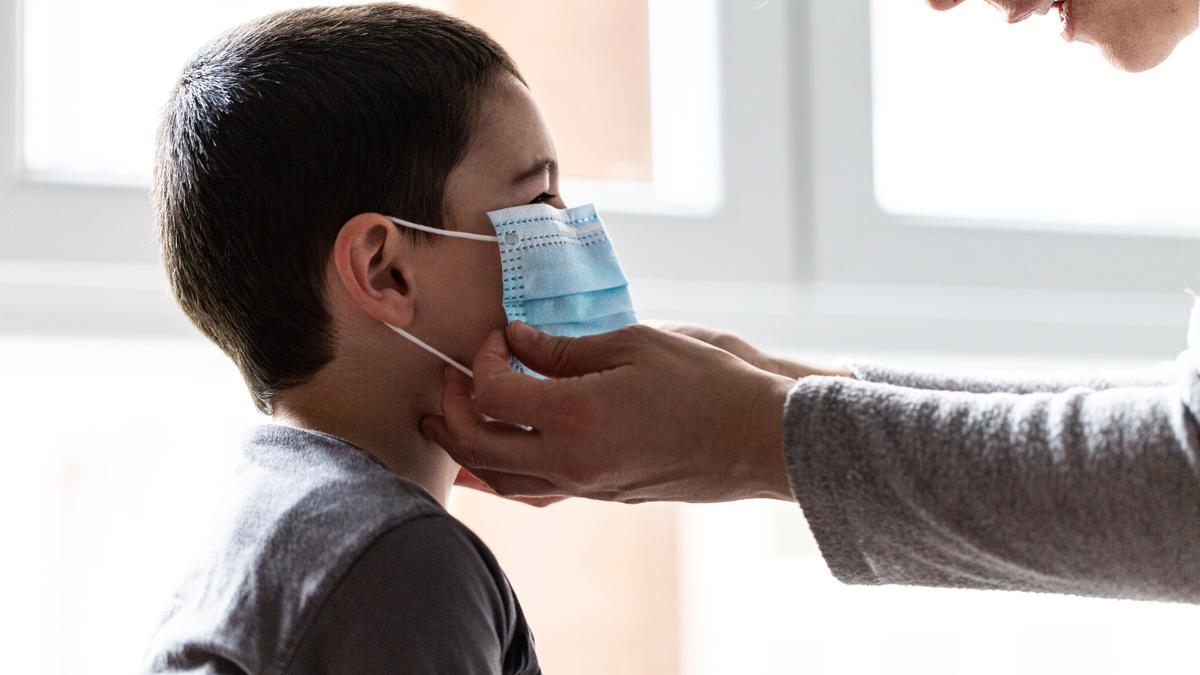 Una persona ajusta la mascarilla a un niño. / Iñaki Verasaluce